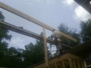 Carpenter setting a ridge beam over a new addition frame — Ice Dam Removal by Roofing Brothers in Ursa