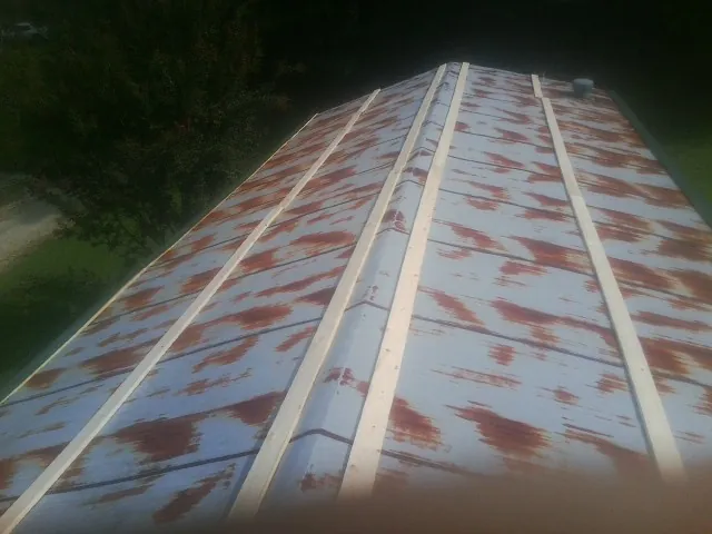 Rusted metal roof panels with new wood purlins before replacement — Storm Damage Roof Repair in Ursa by Roofing Brothers