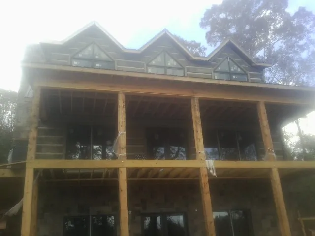 Dormers and porch framing on a large log home under construction — Roof Coating work by our crew in Ursa