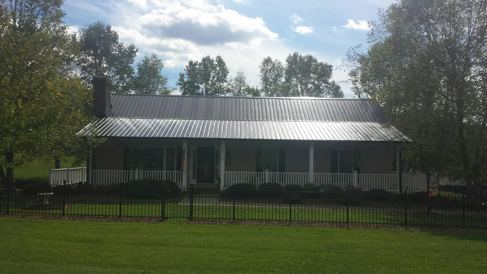Gray metal roof on a brick ranch with a full width front porch — Gutter Guard Installation work by our crew in Ursa
