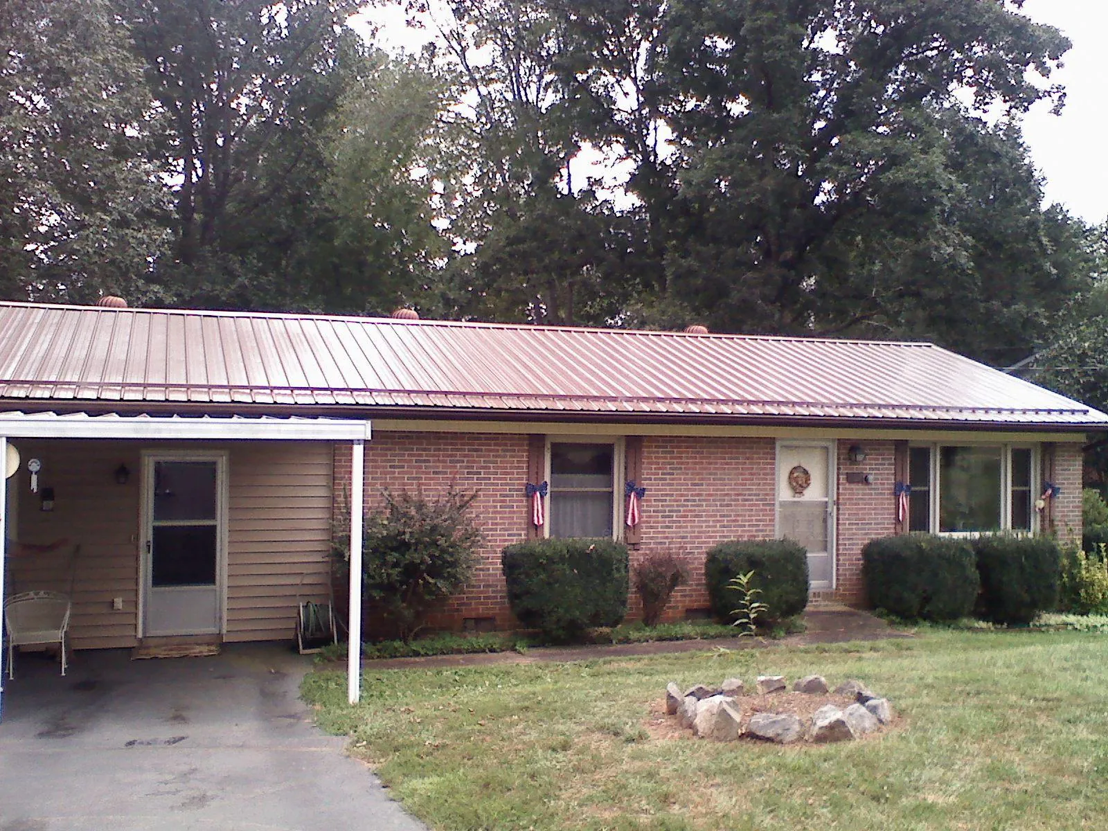 Bronze metal roof and carport on a brick ranch home — Roof Repair work by our crew in Ursa